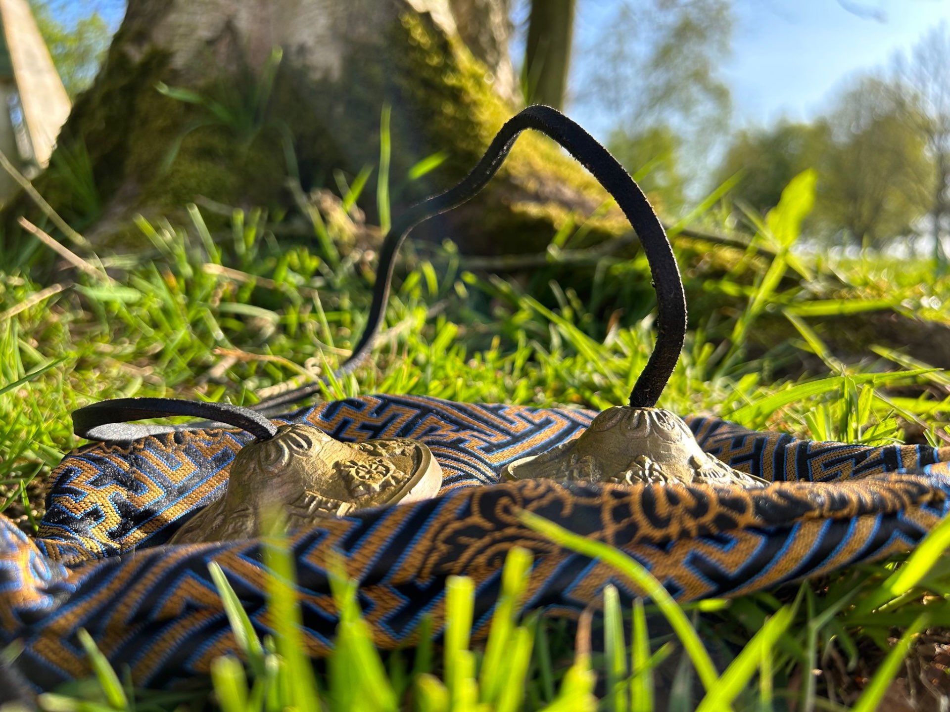 Tibetan tingsha bells resting on a patterned cloth in the grass